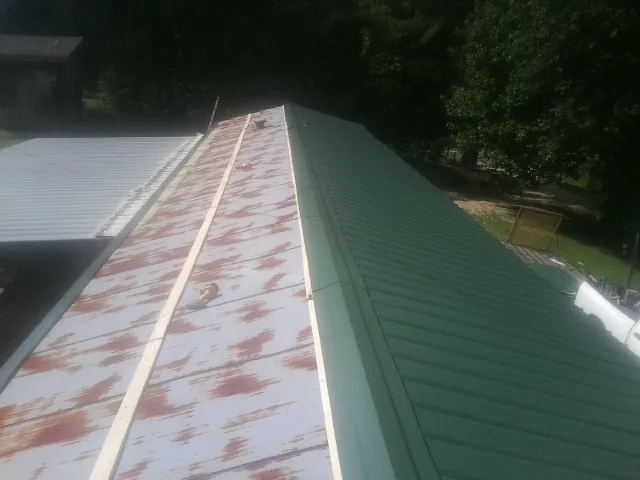 Old rusted panels beside newly installed green metal roofing — Wind Damage Roof Repair by Roofing Brothers in Oviedo