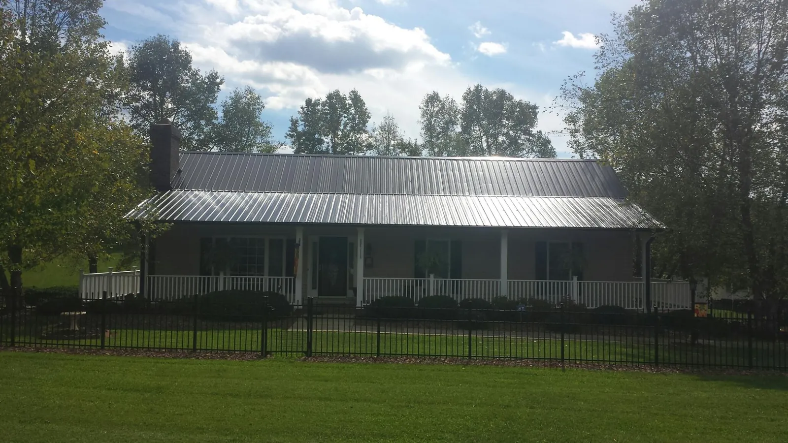 Gray metal roof on a brick ranch with a full width front porch — Gutter Guard Installation work by our crew in Oviedo