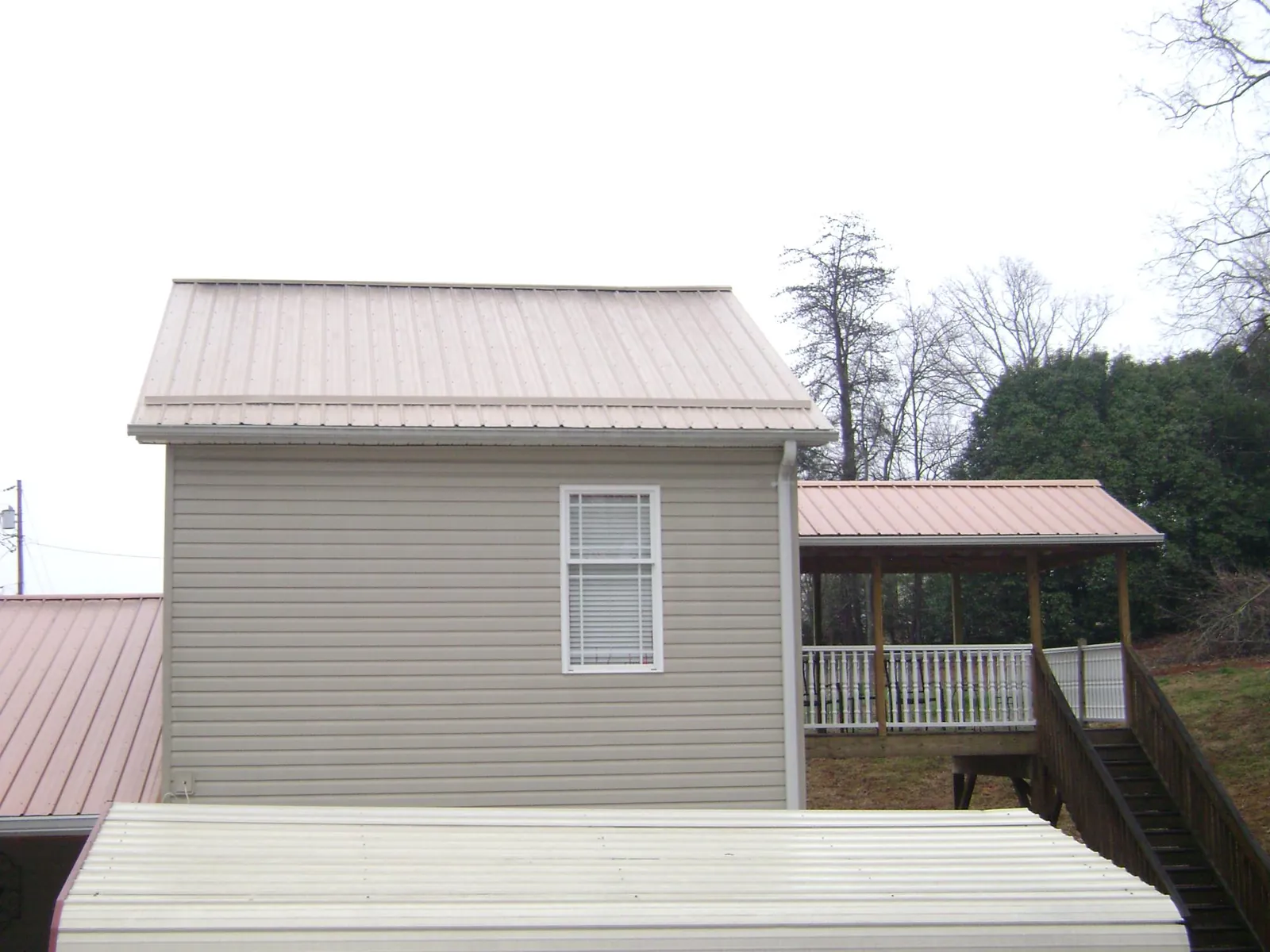 Tan metal roofs on a two story addition and attached porch, from a Roof Replacement job in Oviedo
